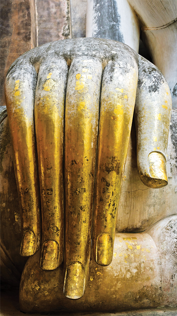 Mano bañada en pan de oro de una antigua estatua de Buda, símbolo de la herencia tailandesa de sanación